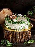 matcha flavoured cake on a wooden cutting board with white vanilla frosting, leaf decorations and chocolate eggs on it