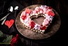 heart shaped valentines day cake topped with candies and sprinkles sitting on a plate with hearts and roses